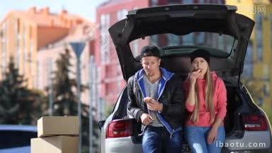 <strong>一对</strong>微笑的夫妇坐在现代汽车的后备箱里，在搬进他们的新公寓期间吃零食